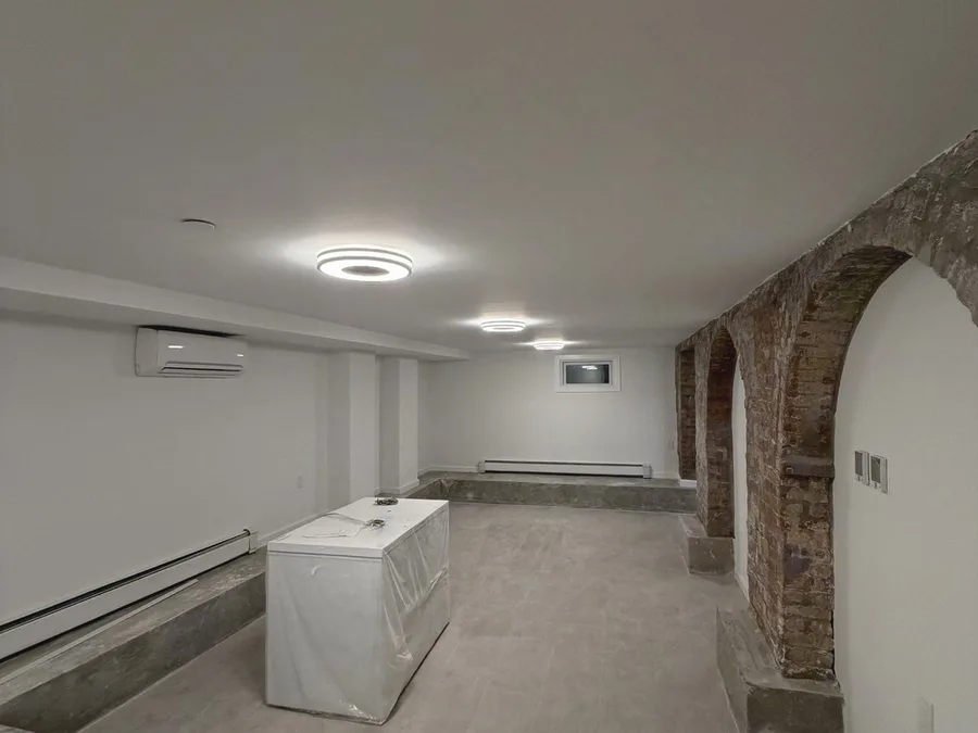 Finished NYC apartment renovation with restored brick arches, new lighting, finished walls, and tile floor