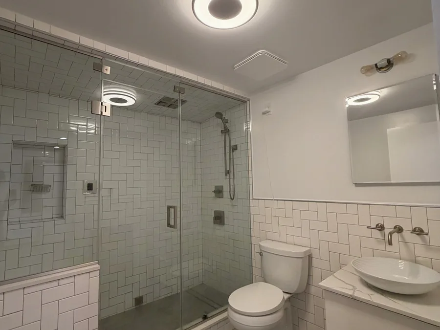 Finished bathroom remodel in NYC with glass shower, subway tile, modern vanity, and tile floor
