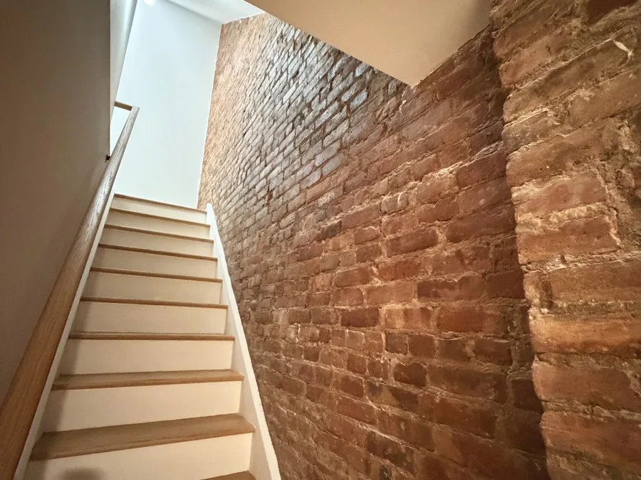 Finished brick stair and hallway renovation with new flooring, paint, and exposed brick details