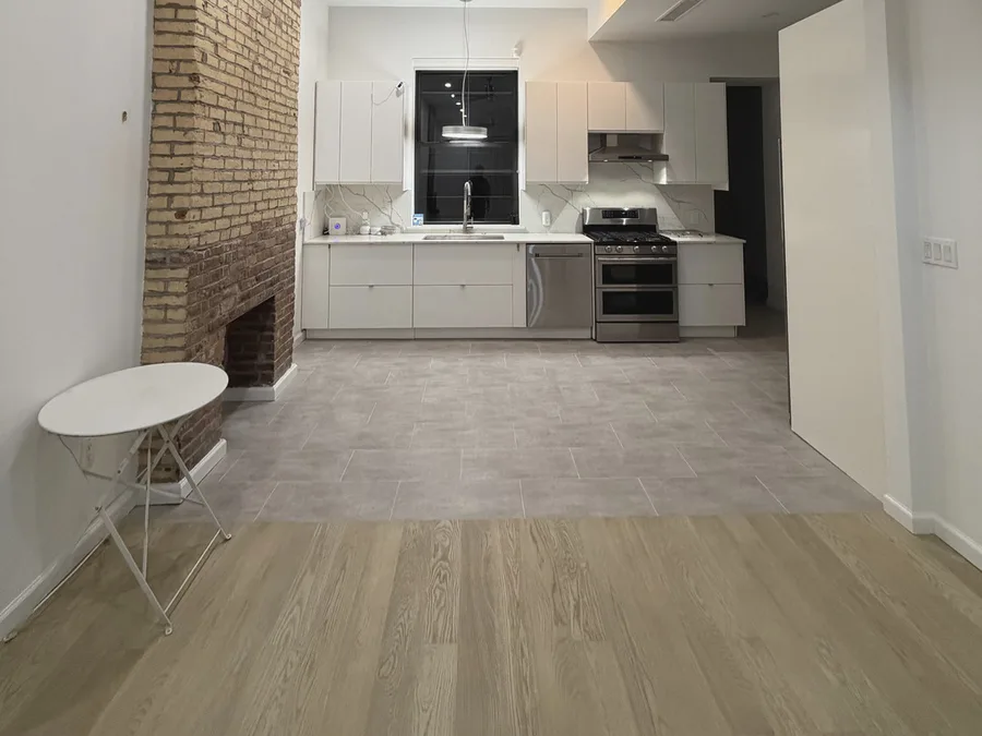 Finished NYC apartment flooring installation with wood flooring, tile transition, and clean trim details