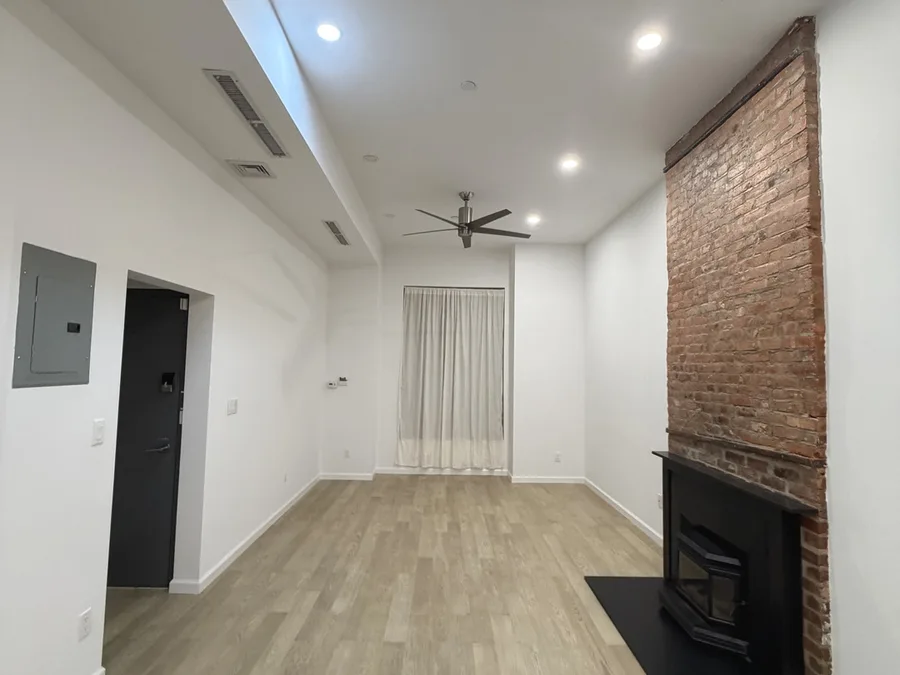 Finished living room renovation in NYC with smooth painted walls, recessed lighting, and clean trim work
