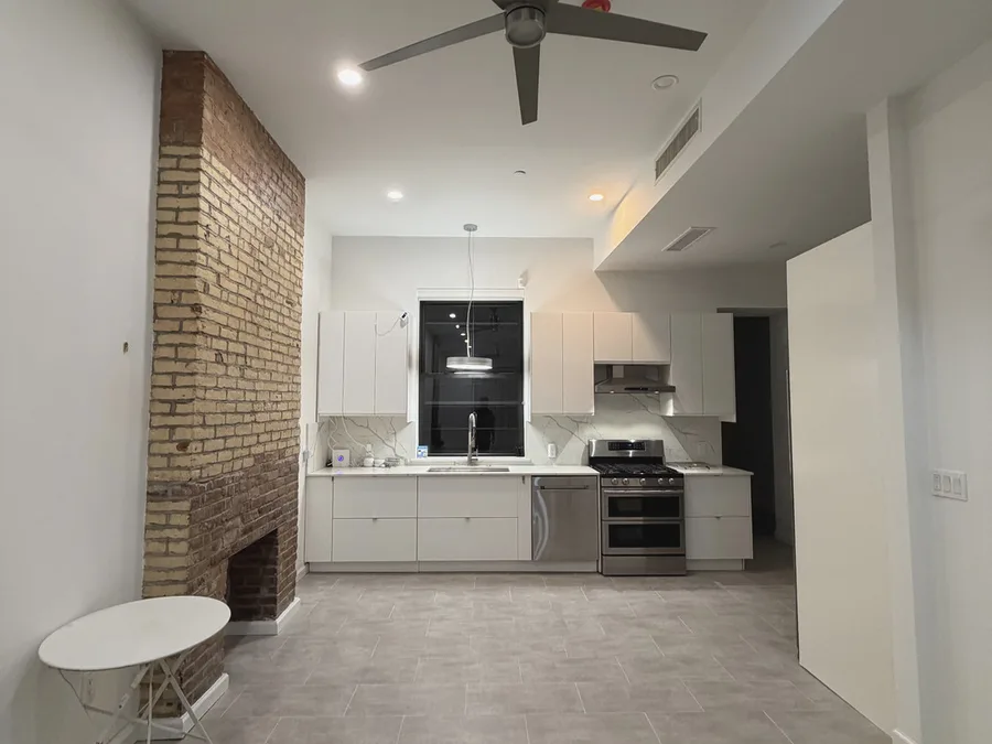Finished full apartment renovation in NYC with open living room, kitchen, exposed brick, and new flooring